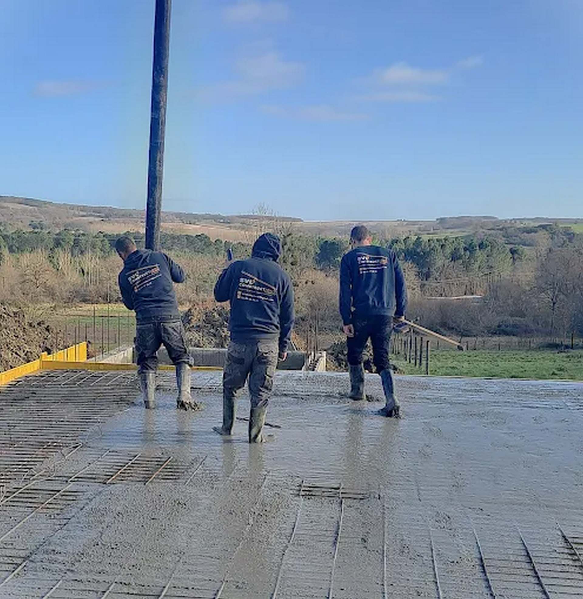 Ouvriers de SVD Construction coulant une dalle de béton sur un chantier de maçonnerie en extérieur.